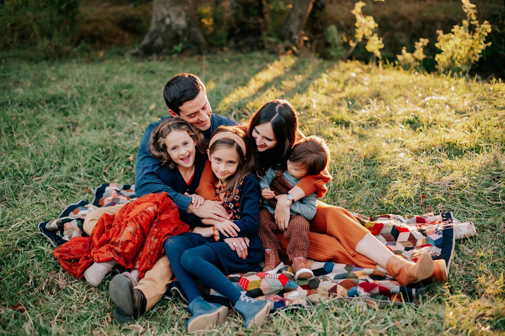 Family sitting together on a quilt outdoors
